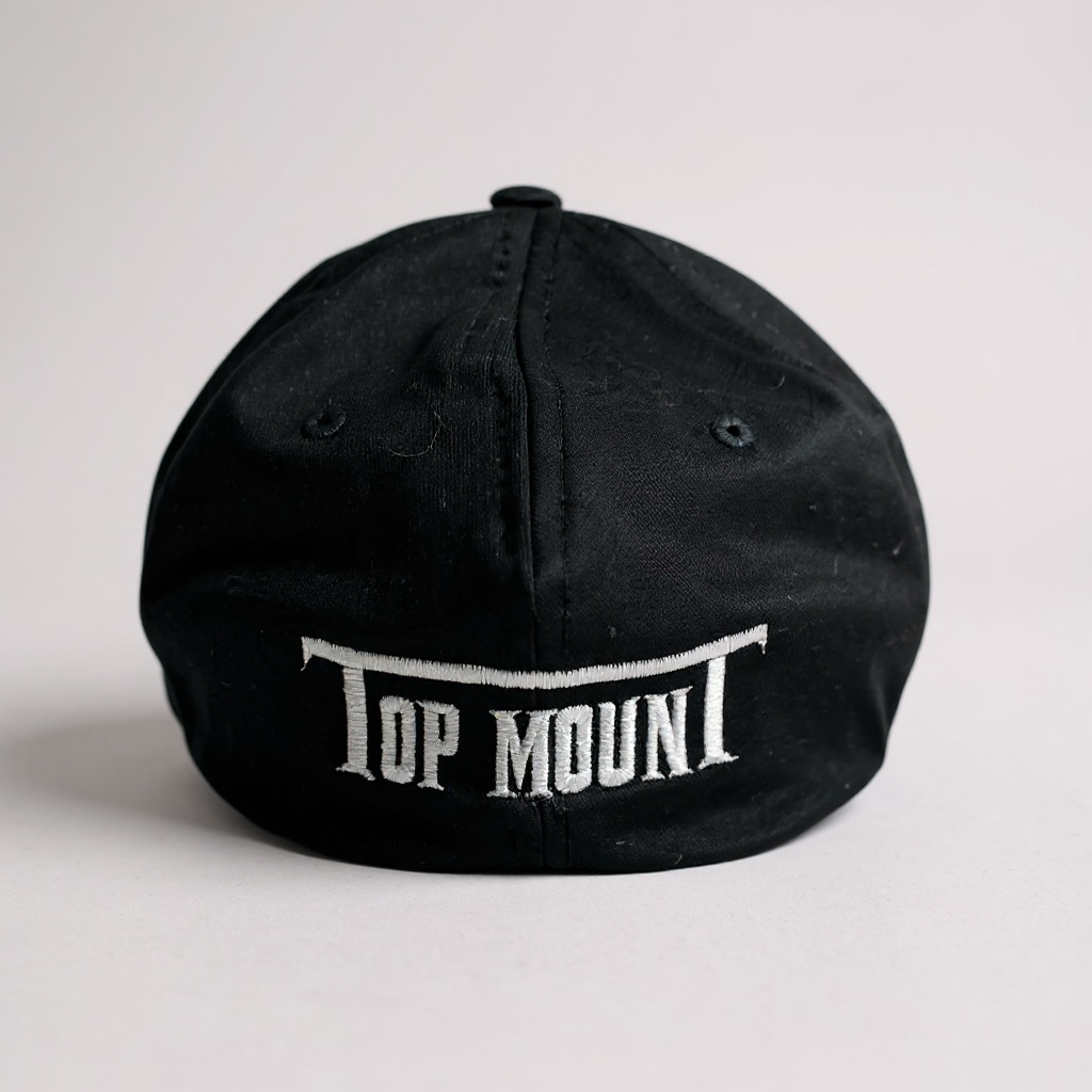 Rear view of a black BJJ Flex Fit hat with white Top Mount embroidery on a structured mid-profile crown.