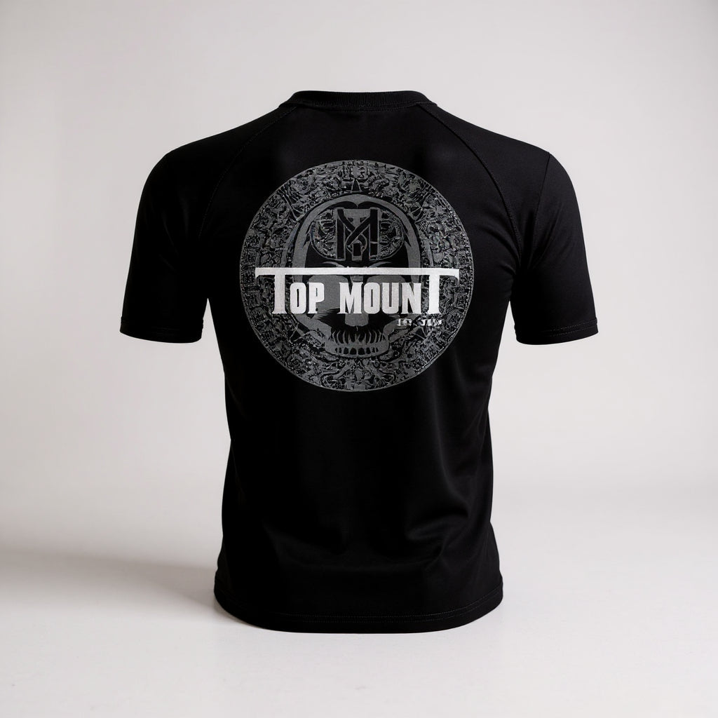 Back view of black Youth Aztec BJJ Rashguard with gray Aztec calendar graphic and white Top Mount logo for kids MMA.