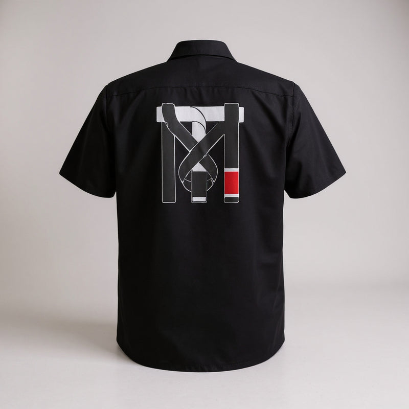 Back of black Mechanic Crew Work Shirt featuring the Top Mount TM jiu-jitsu belt logo graphic in white and red.