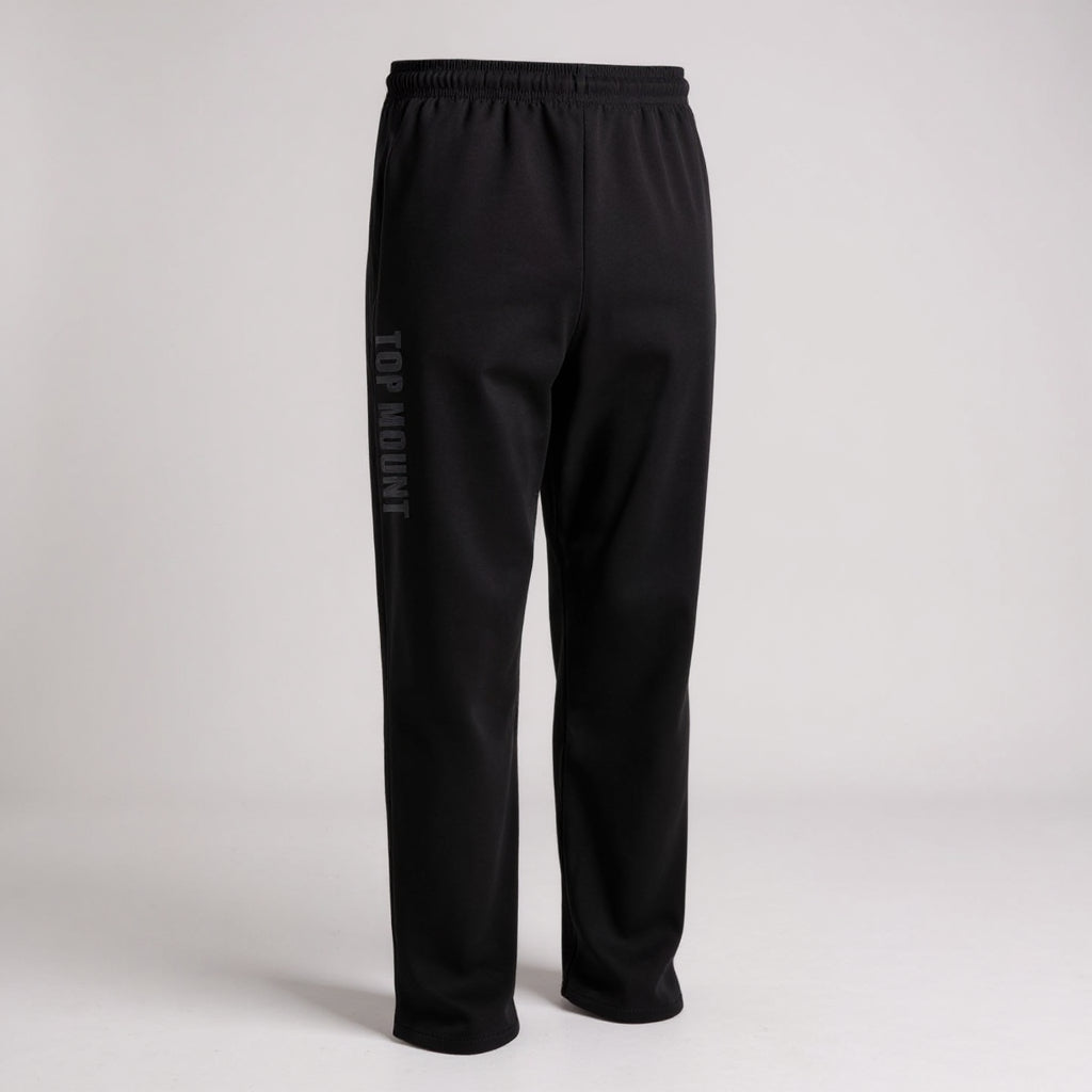 Black BJJ warm-up joggers featuring a Top Mount vertical leg logo, elastic waistband, and a relaxed recovery fleece fit.